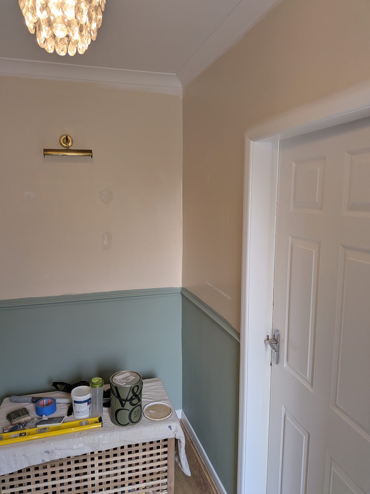 A landing with a cream upper wall, spruce green dado and a white panelled door