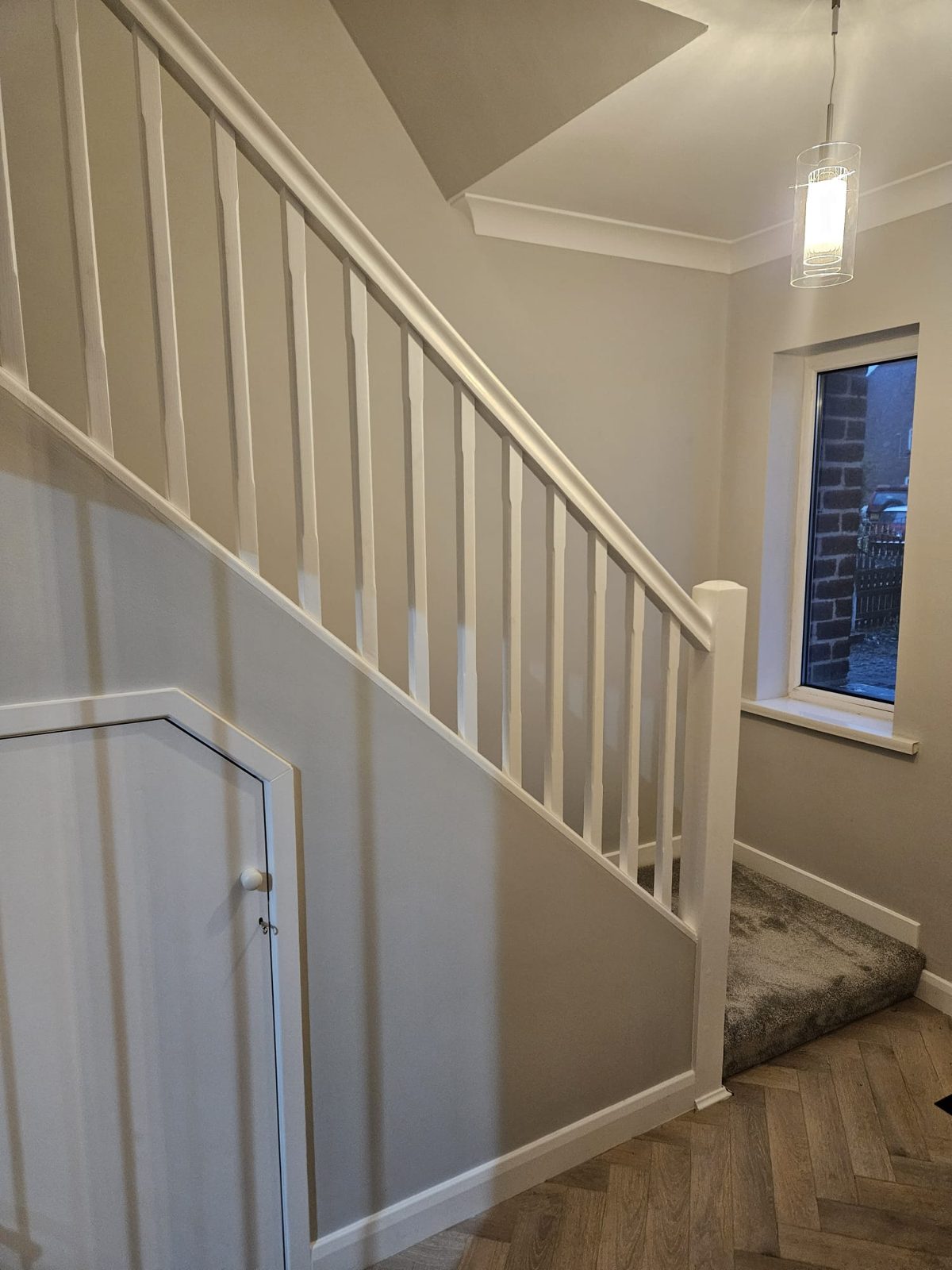 A white painted staircase with spindles beside a soft grey wall