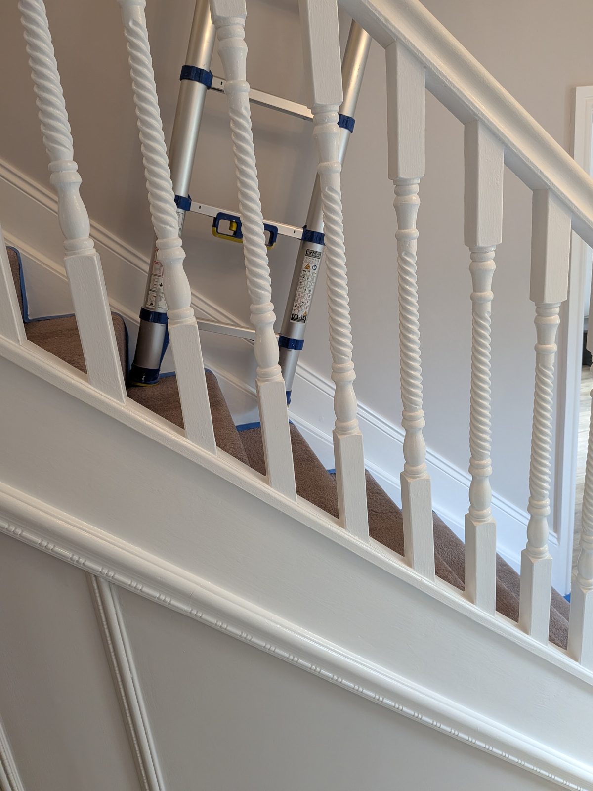 Close up of white spindles and a panelled dado on a freshly painted staircase